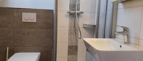 Regadera, secadora de cabello, toallas, papel de baño