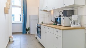 Eine moderne Küche mit weißen Schränken, einer Mikrowelle, einer Kaffeemaschine und einem Spülbecken.
