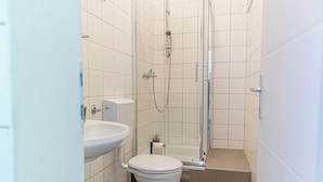 Ein kleines, sauberes Badezimmer mit Toilette, Waschbecken und Dusche.