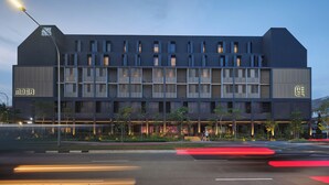 A modern building with multiple balconies, a prominent 'MBER' sign, and a street view with light trails. - Mber Co-Living Serviced Apartments (Singapore)