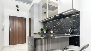 Uma cozinha moderna com bancada de mármore, coifa de aço inoxidável e dois banquetas.