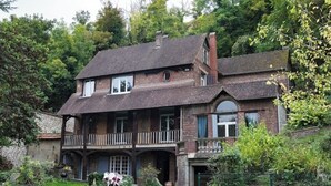 A two-story brick house with a balcony, surrounded by lush greenery. - Large 10-bedroom manor house, sleeps up to 20—view of the Seine, Les Andelys, 1 hour from Paris (Les Andelys)