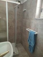 Un baño con ducha, bañera y barra para toallas.