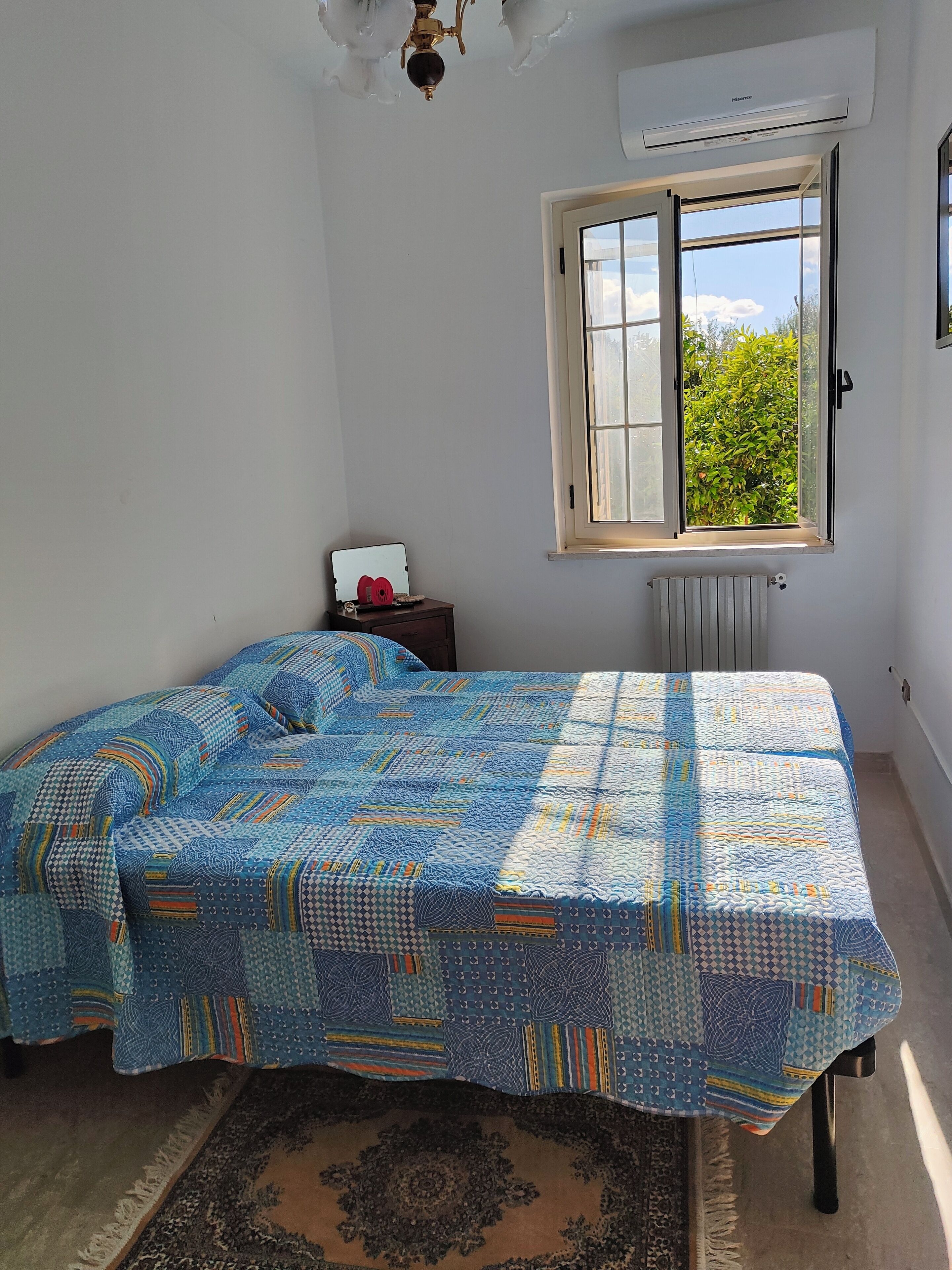 Une chambre à coucher avec un lit, une fenêtre, un radiateur et une petite table sur laquelle se trouve un ordinateur portable.