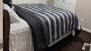 Ein Schlafzimmer mit einem Bett, einem weißen Kopfende, einer Tür und einer Deckenleuchte.
