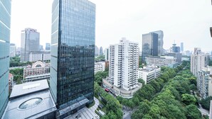 Un immeuble de grande hauteur à la façade vitrée, entouré d’autres bâtiments imposants et de verdure.