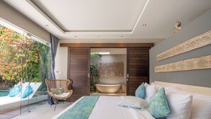Een moderne slaapkamer met een groot bed, een badkuip en een glazen balkon met uitzicht op een tuin.