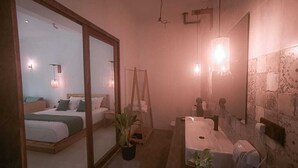 A modern hotel room with a large bed, a bathroom with a sink and mirror, and a potted plant. - Cozy Beach Talalla  (Talalla)