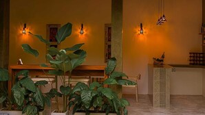 A reception area with a wooden bench, potted plants, and patterned wall sconces. - Cozy Beach Talalla  (Talalla)