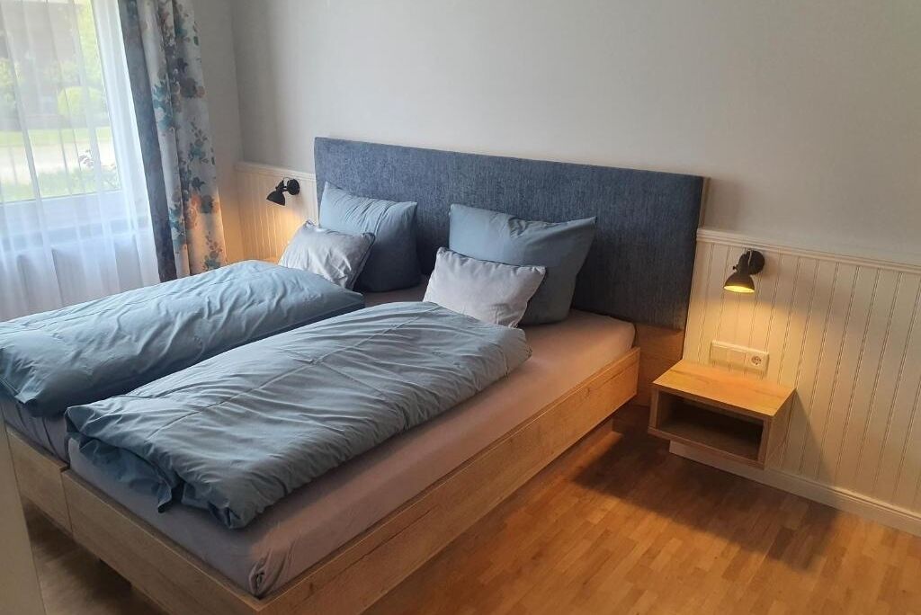 Quarto com cama, almofadas, mesas de cabeceira e janela com cortinas.
