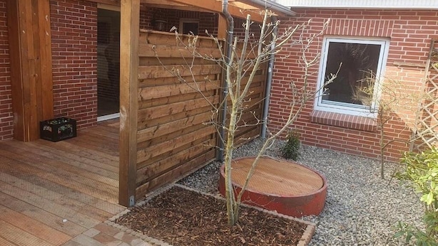 Una terraza de madera con un edificio de ladrillo al fondo.