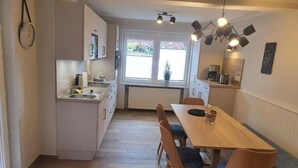 Una cocina funcional con una mesa y sillas de madera, horno empotrado y ventana con vistas al exterior.