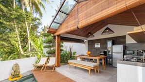 A modern kitchen with a stone backsplash, wooden furniture, and a built-in refrigerator. - Villa Temple Tree By Soobali - UBUD (Ubud)