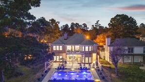 A large house with a swimming pool, outdoor seating, and a well-lit entrance. - Lake it easy, Fish, Kayak, Yard, Boat, Sleeps 20 (Montgomery)