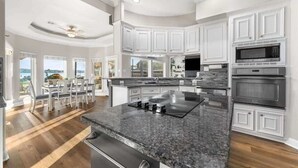 A modern kitchen with white cabinetry, a granite countertop, stainless steel appliances, and a dining area with a view. - Lake it easy, Fish, Kayak, Yard, Boat, Sleeps 20 (Montgomery)
