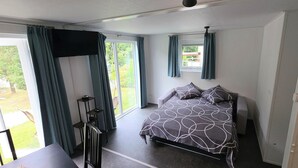 A bedroom with a bed, a TV mounted on the wall, and a sliding glass door leading to a patio.