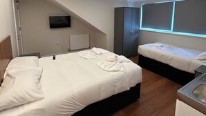A modern hotel room with two beds, a flat-screen TV mounted on the wall, and a small kitchenette. - Buckingham Annexe (High Wycombe)