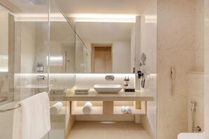 A modern bathroom with a glass shower enclosure, a large mirror, a sink with a vanity, and a toilet. - Regenta Hotel Science Center Bhuj (Bhuj)