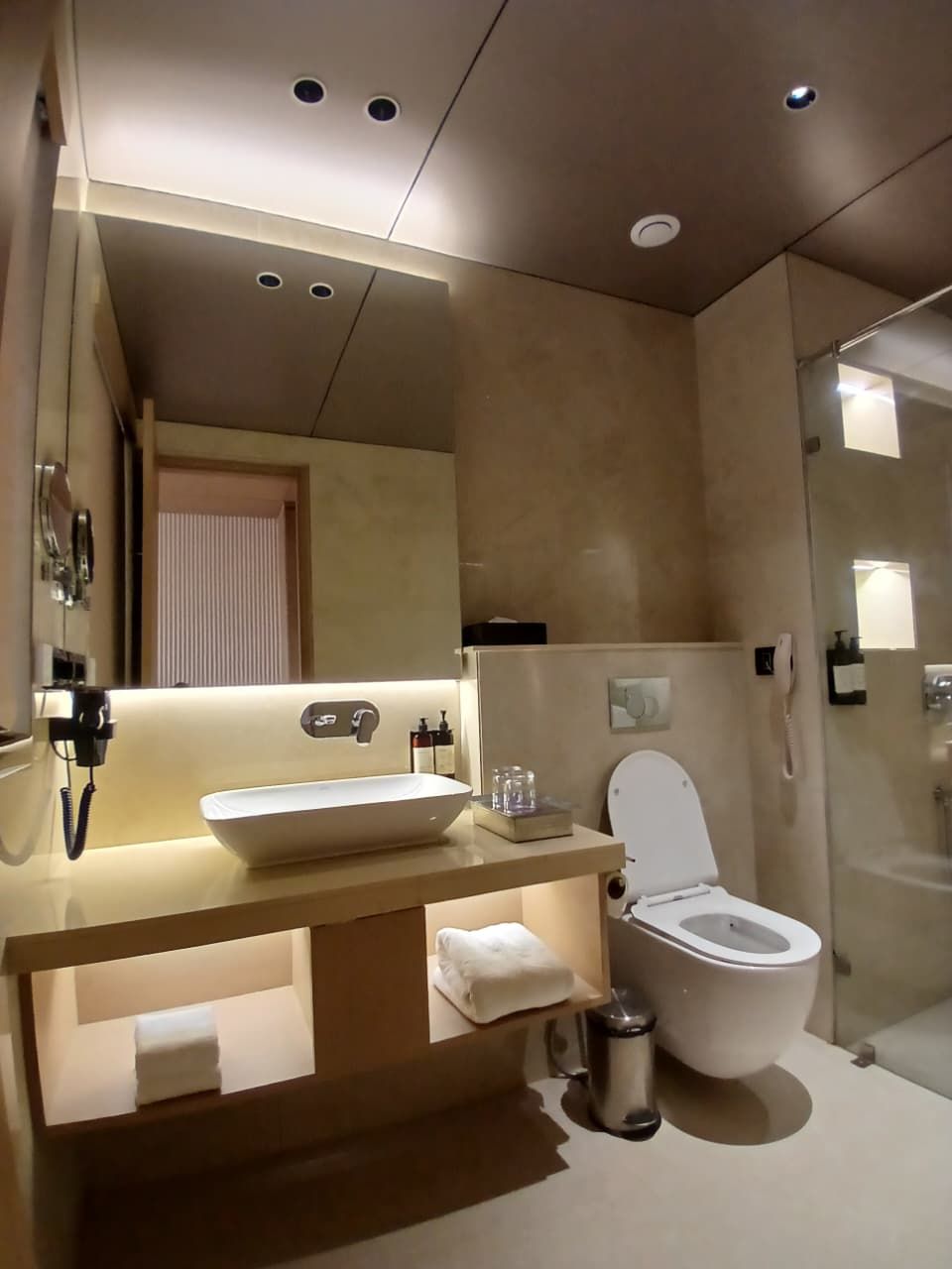 Un baño moderno con un espejo grande, un lavabo sobre encimera, un inodoro y una zona de ducha.