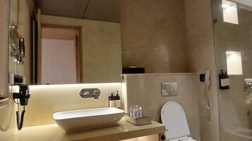 Un baño moderno con un espejo grande, un lavabo sobre encimera, un inodoro y una zona de ducha.