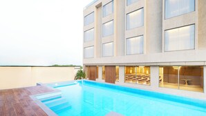 A modern hotel with a swimming pool, wooden deck, and large windows. - Regenta Hotel Science Center Bhuj (Bhuj)