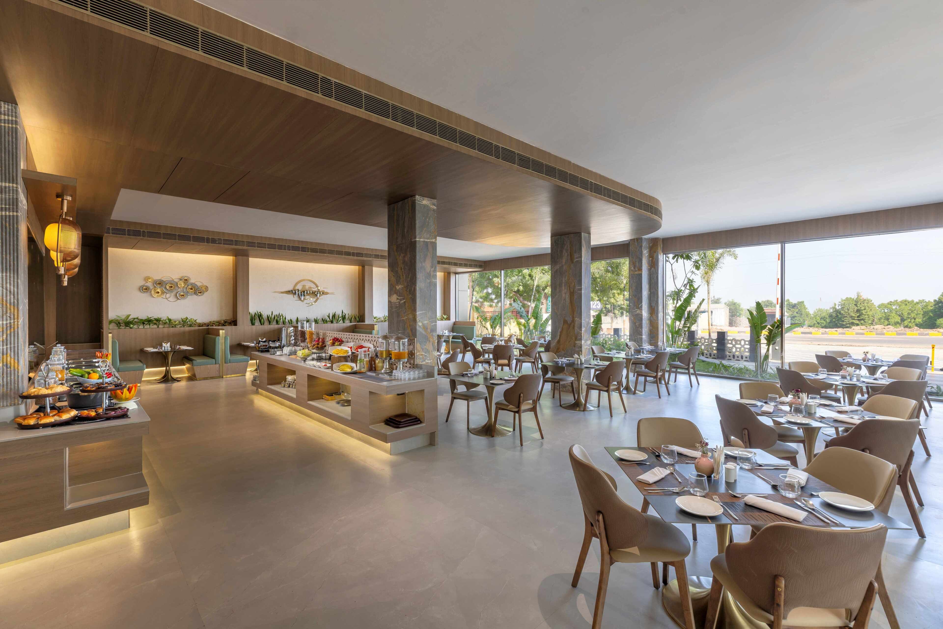 A spacious dining area with multiple tables and chairs, a buffet counter, and a view of the outdoors.