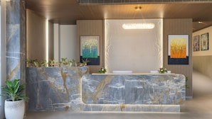A reception area with a marble reception desk, potted plants, and framed artwork on the walls. - Regenta Hotel Science Center Bhuj (Bhuj)