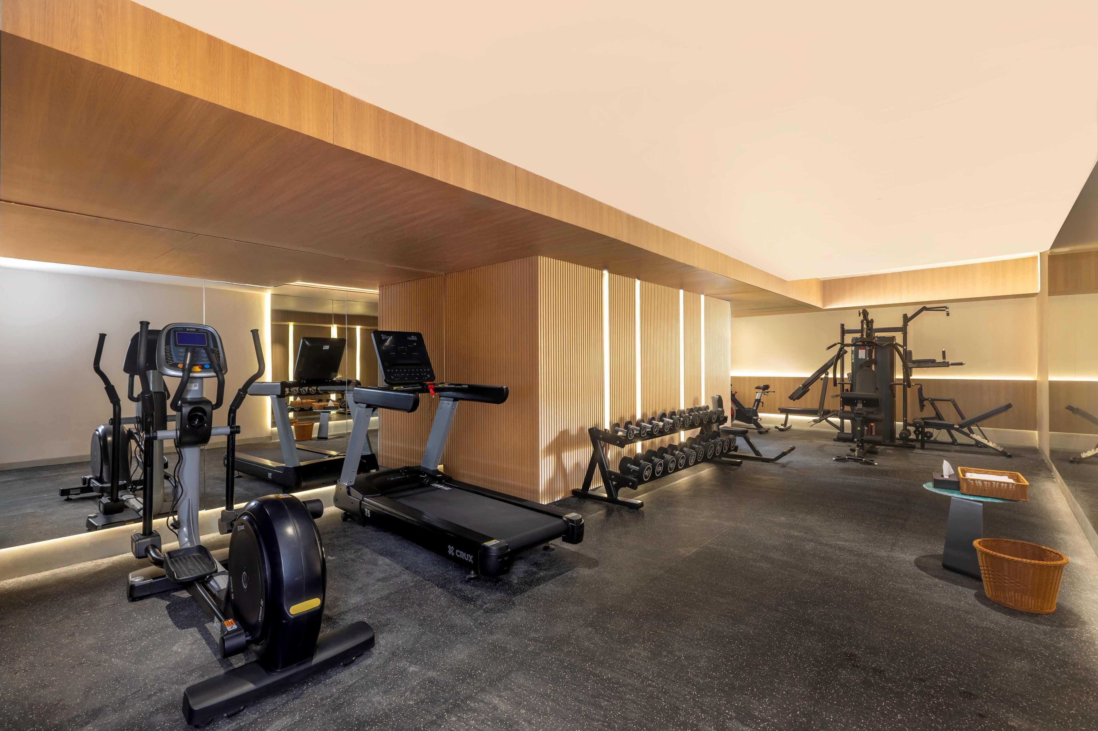 A modern gym with treadmills, ellipticals, and free weights.