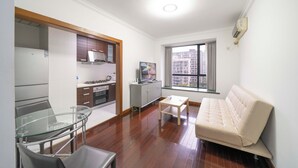 Una sala moderna con un sofá, una mesa de vidrio y una zona de cocina con armarios y estufa.