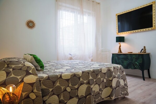 A bedroom with a bed, a nightstand, a lamp, a Buddha statue, and a wall-mounted TV. - Gabri's House has 3 rooms with 3 private bathrooms and a kitchen available (Rozzano)
