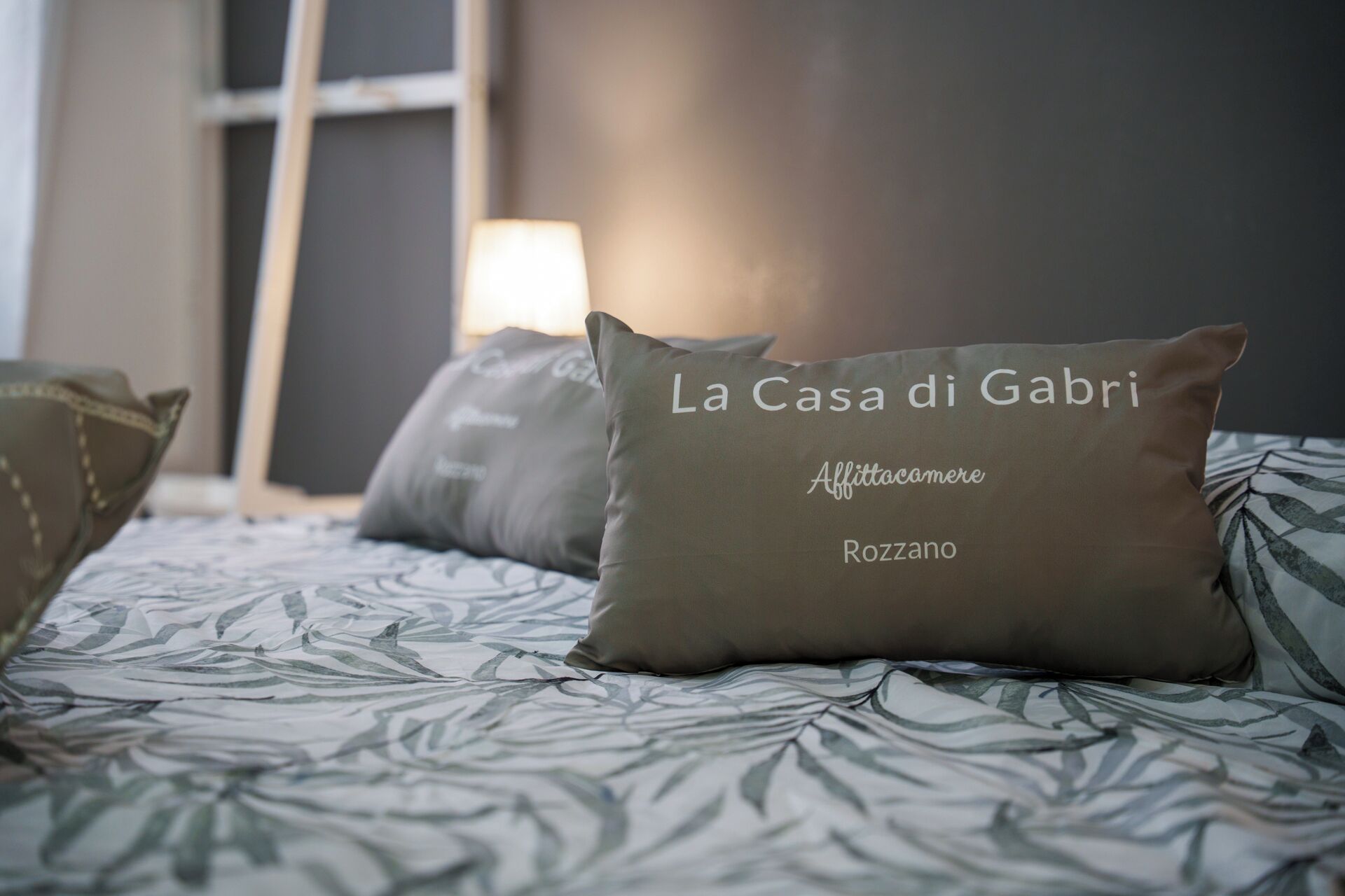 A bed with patterned bedding and pillows labeled "La Casa di Gabri."