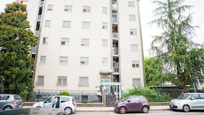 A multi-story residential building with balconies, a gated entrance, and parked cars. - Gabri's House has 3 rooms with 3 private bathrooms and a kitchen available (Rozzano)