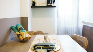 A dining table with a decorative runner, a gold wire basket with rolled-up mats, and a black kettle on a shelf above. - Gabri's House has 3 rooms with 3 private bathrooms and a kitchen available (Rozzano)