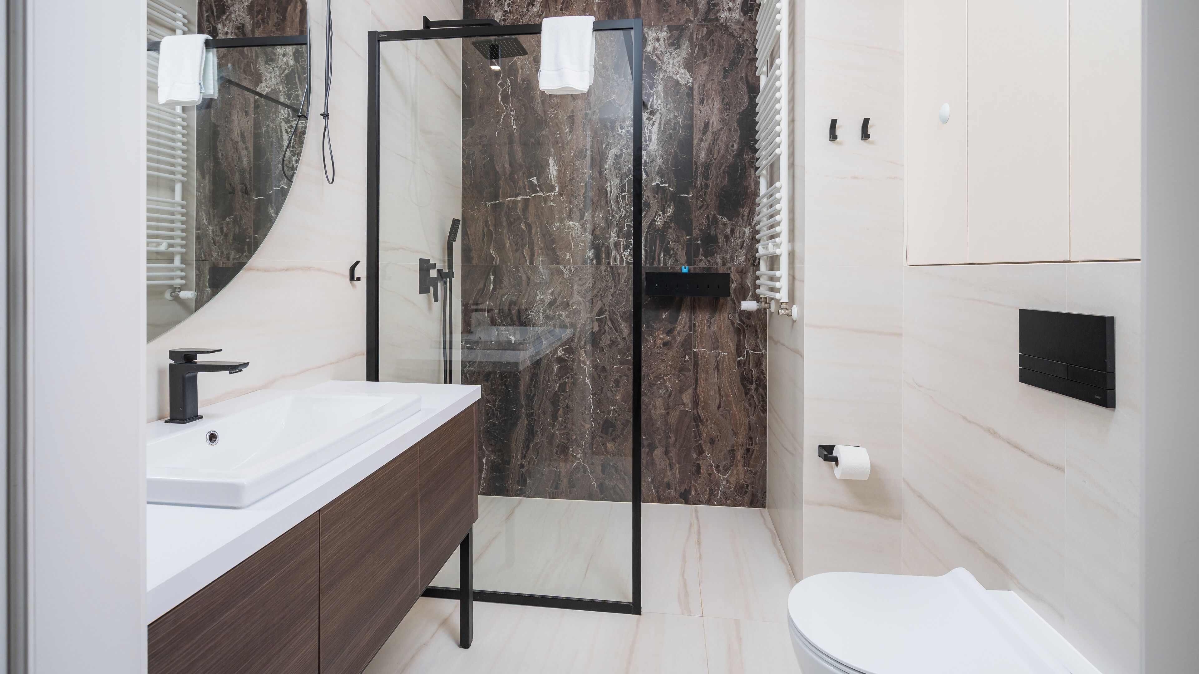 A modern bathroom with a glass-enclosed shower, a white sink, and a toilet.