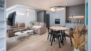 Een moderne woonkamer met een bank, salontafel en een eethoek.