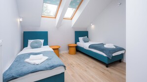 Een moderne slaapkamer met twee bedden, een dakraam en uitzicht op de lucht.