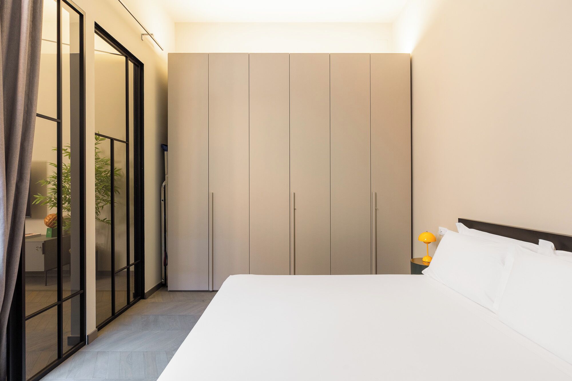 Een hotelkamer met een bed, een kledingkast en een schuifglazen deur naar een balkon.