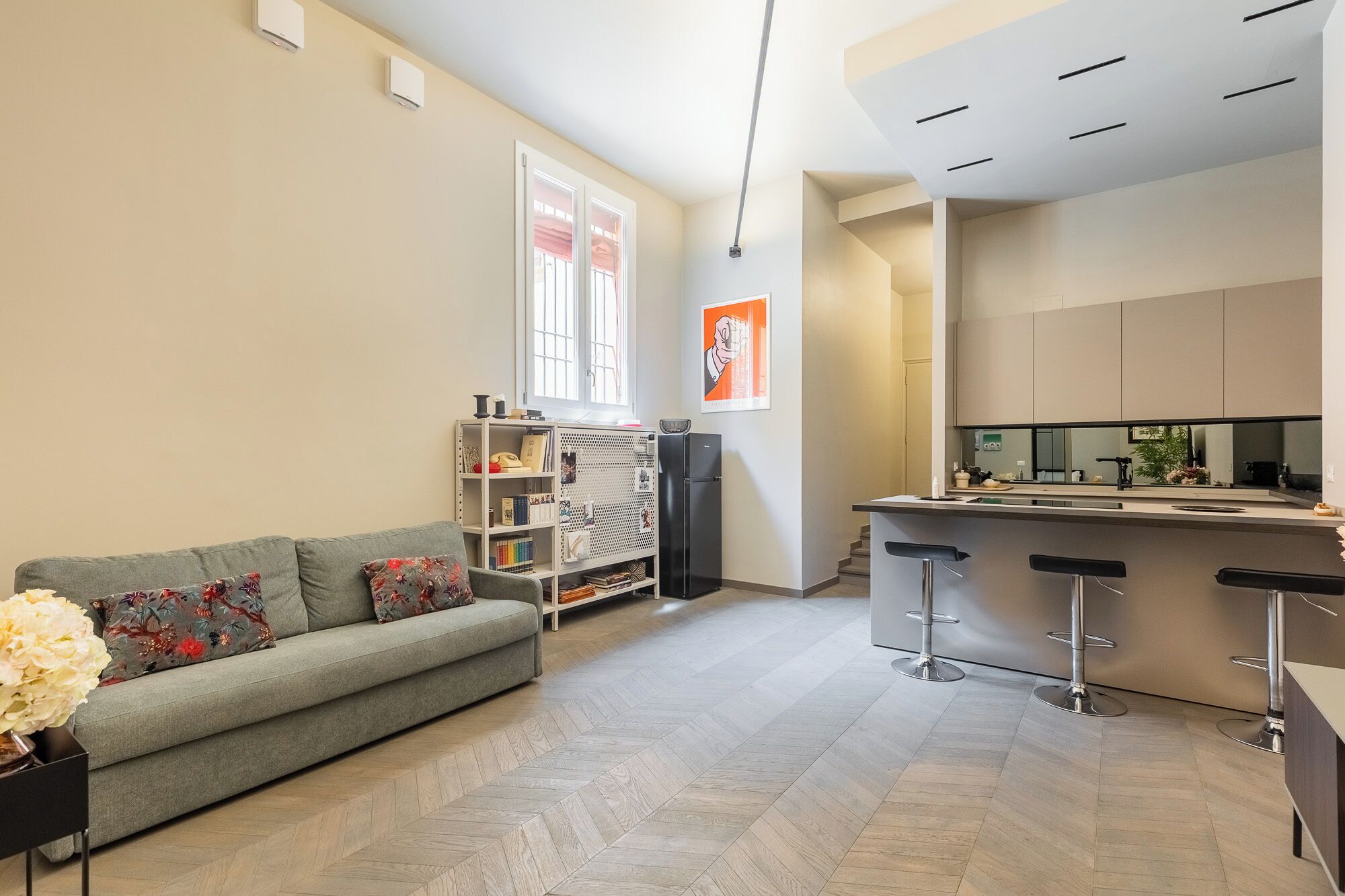Un salon moderne avec un canapé, une bibliothèque et un coin cuisine doté d’un bar.