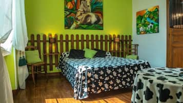 A room with a bed, a small table, and two paintings on the wall.