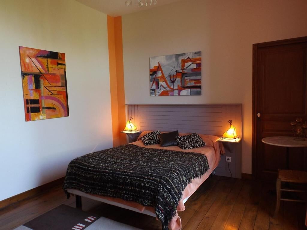 Una camera da letto con un letto, due lampade ai comodini, una testiera e due dipinti astratti alle pareti.
