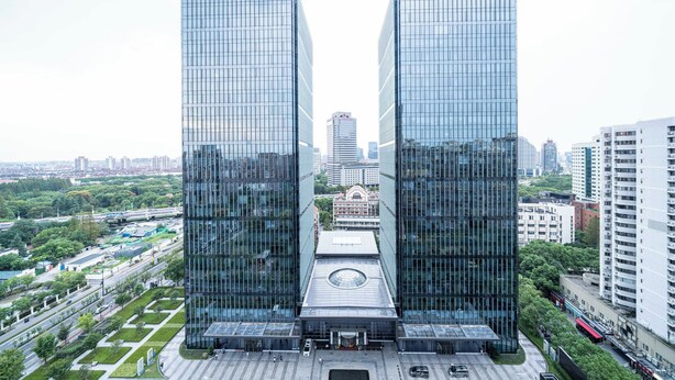 A modern skyscraper with a symmetrical design, featuring a central plaza with a circular skylight. - Tyms Stylish 1BR APT  Yucui Garden (Shanghai)