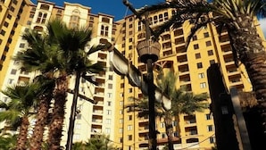 A high-rise building with multiple balconies and palm trees in the foreground. - 4th of July Near Disney (Lake Buena Vista)