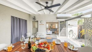 A dining area with a wooden table set for a meal, a ceiling fan, and a view of the backyard. - Capri Blue 2, 88 Tomaree Rd - stunning townhouse with Wi-Fi, Air Con (Shoal Bay)