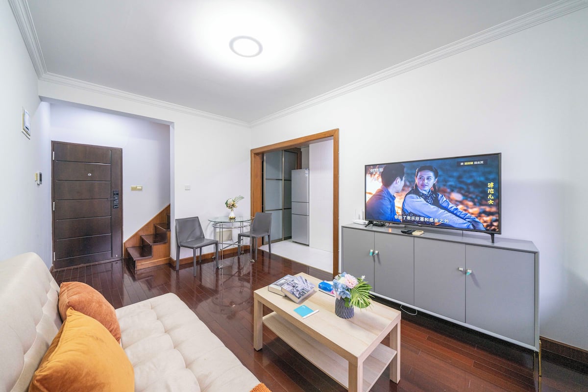 Een woonkamer met een bank, salontafel, televisie en een grijze kast.