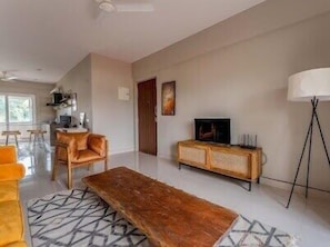 A modern living room with a wooden coffee table, a sofa, a TV on a cabinet, and a lamp.