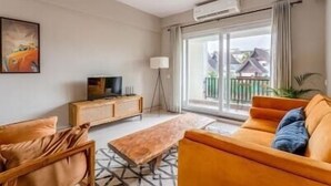 Una sala de estar moderna con un sofá, una mesa de centro y un televisor sobre un mueble de madera.