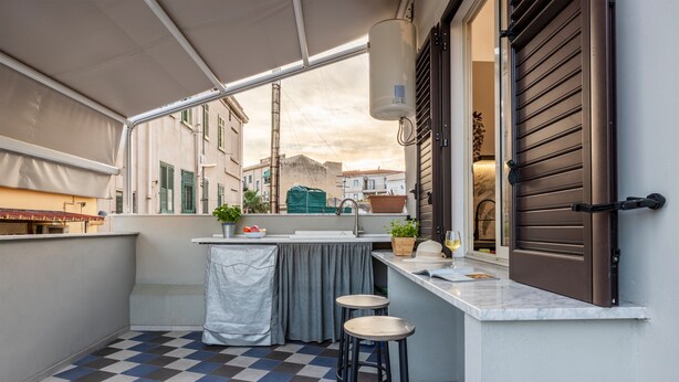 A compact balcony with a checkered floor, a small bar area, and a view of the cityscape. - Fiorelli 17 - Blue Peafowl Studio with Private Terrace and Wi-Fi (Palermo)