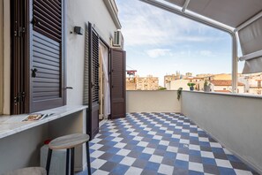 A balcony with a checkered floor, a table, and a chair.
