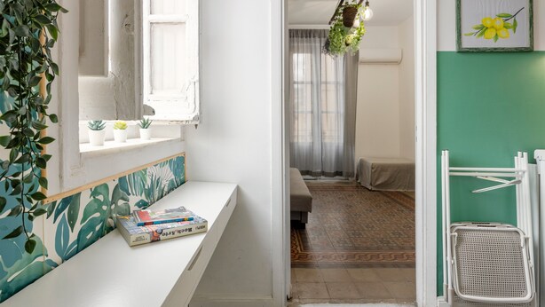 A room with a white bench, a window with potted plants, a hanging light fixture, and a green wall. - 'Fiorelli 17 - Bivano Green Leaves' Apartment with Balcony, Wi-Fi and Air Conditioning (Palermo)