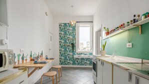 A modern kitchen with a green accent wall, wooden stools, and a built-in microwave. - 'Fiorelli 17 - Bivano Green Leaves' Apartment with Balcony, Wi-Fi and Air Conditioning (Palermo)